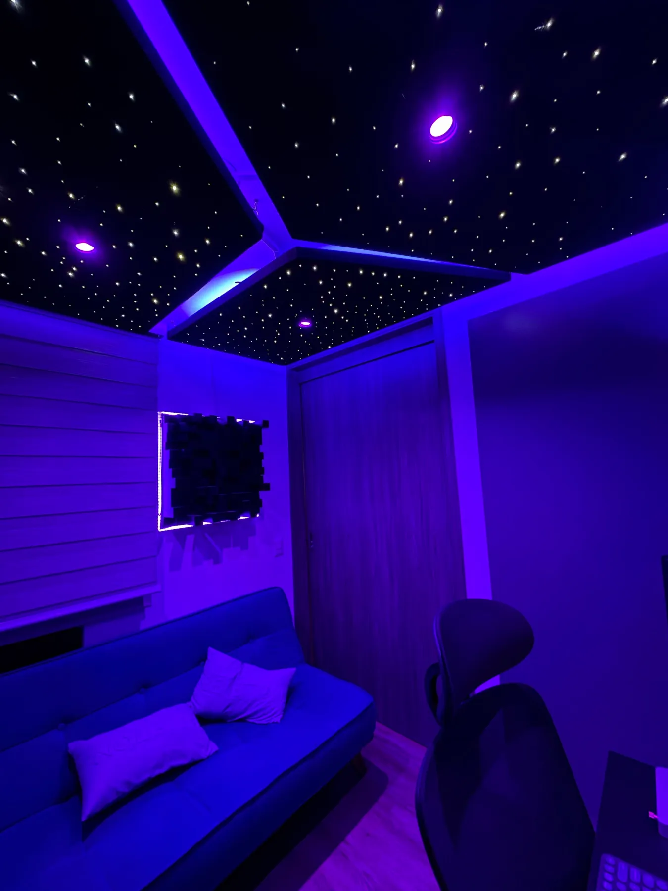 Sala con techo de fibra óptica y difusor acústico iluminado en la pared